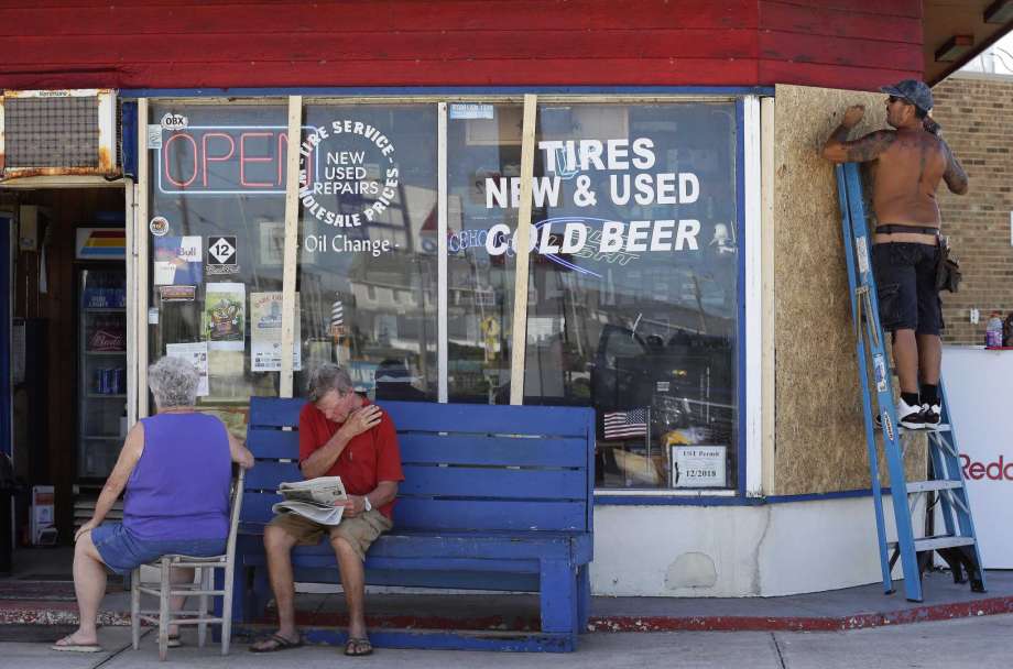 As store windows are prepped with plywood a couple waits for their automobile in Nags Head, N.C., Wednesday, Sept. 12, 2018, as Hurricane Florence approaches the coast of the Carolinas. The National Weather Service says Hurricane Florence "will likely be the storm of a lifetime for portions of the Carolina coast." Photo: Gerry Broome, AP / Copyright 2018 The Associated Press. All rights reserved