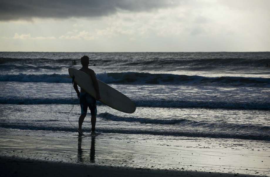A surfer looks out to the waves in the early morning at the Isle of Palms, S.C., as Hurricane Florence spins out in the Atlantic ocean Wednesday, Sept. 12, 2018. The National Weather Service says Hurricane Florence "will likely be the storm of a lifetime for portions of the Carolina coast." Photo: Mic Smith, AP / Mic Smith Photography LLC