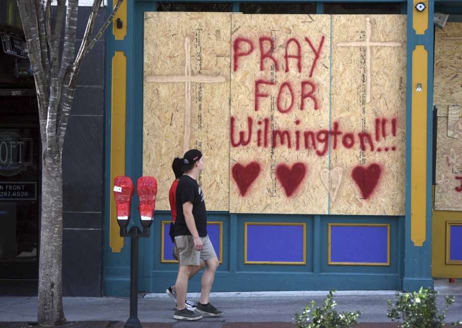 People walk by the boarded up front windows of Bourbon Street in preparation for Hurricane Florence in Wilmington, N.C., Wednesday, Sept. 12, 2018. The effects of Hurricane Florence in Southeastern North Carolina are expected to begin Thursday. (Matt Born/The Star-News via AP) Photo: Matt Born, AP / The Star-News
