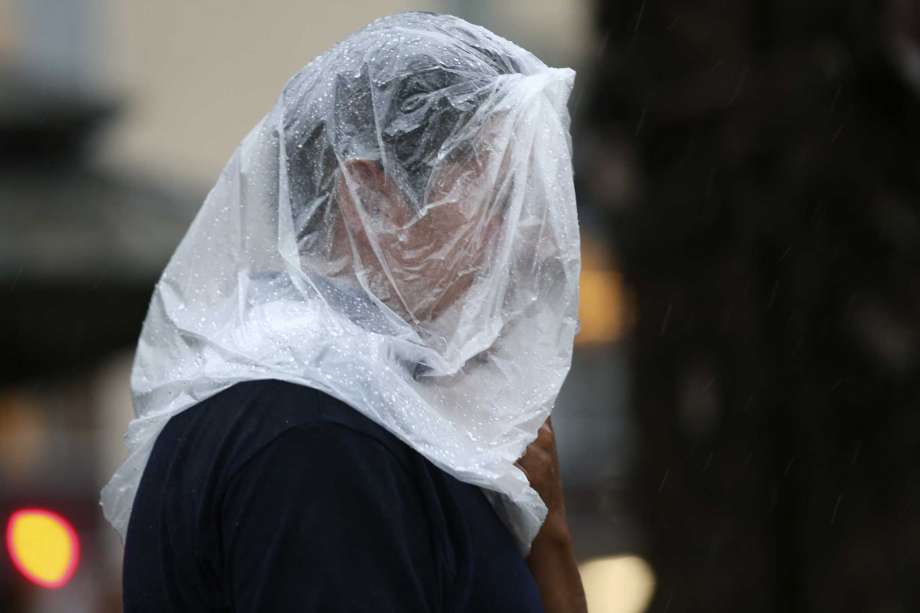 A pedestrians uses a plastic bag as cover during rain fall in downtown San Antonio, Sunday, Sept. 9, 2018. Photo: JERRY LARA, San Antonio Express-News / © 2018 San Antonio Express-News