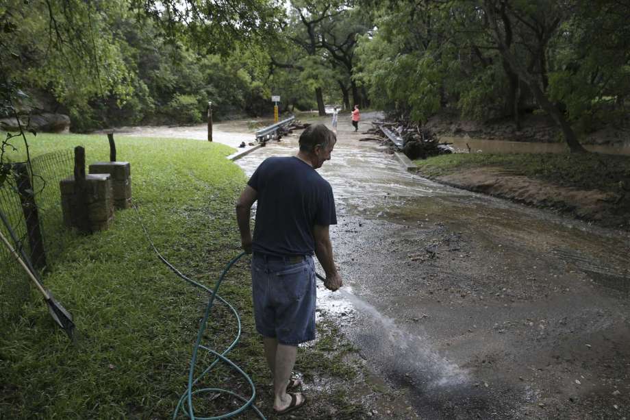 Le Moey Wiebush washes the street in front of his home in Grey Forest after rains causes flooding at low water crossings throughout the town, Sunday, Sept. 9, 2018. A the height of the rain storm, all low water crossings, including the main road leading into Grey Forest, Scenic Loop Road, were closed for several hours. Photo: JERRY LARA, San Antonio Express-News / © 2018 San Antonio Express-News
