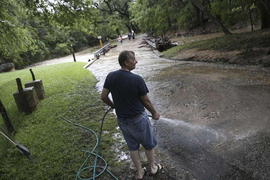 Le Moey Wiebush washes the street in front of his home in Grey Forest after rains causes flooding at low water crossings throughout the town, Sunday, Sept. 9, 2018. A the height of the rain storm, all low water crossings, including the main road leading into Grey Forest, Scenic Loop Road, were closed for several hours. Photo: JERRY LARA, San Antonio Express-News / © 2018 San Antonio Express-News
