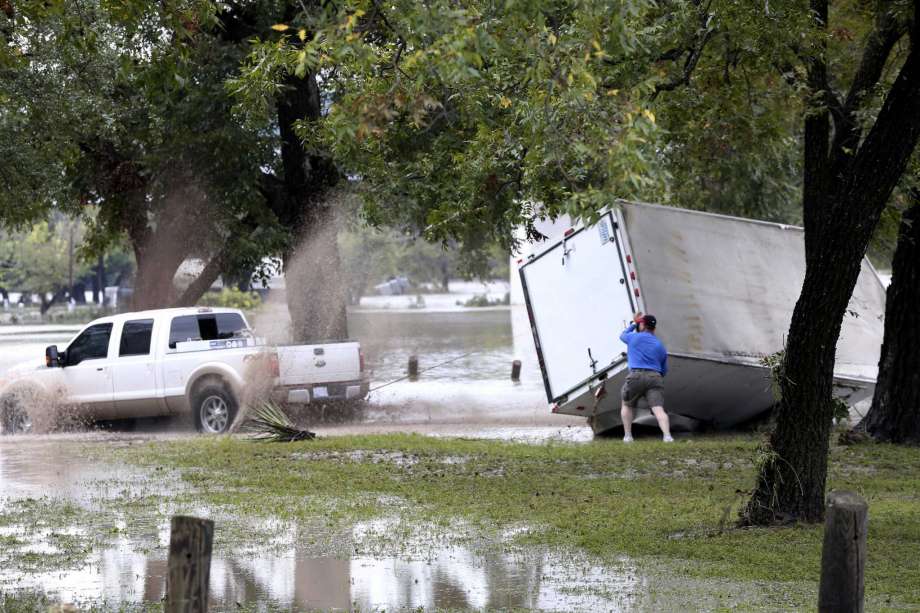 People try to get a trailer back upright Monday on the grounds of the Kimble County River Park in Junction. Photo: Jerry Lara /Staff File Photo / © 2018 San Antonio Express-News