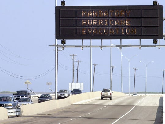 A lone vehicle makes its way out onto the John F. Kennedy Causeway on its way to Padre Island Wednesday, Sept. 21, 2005 after passing under a Mandatory Hurricane Evacuation highway sign for the island and Flour Bluff neighborhood.