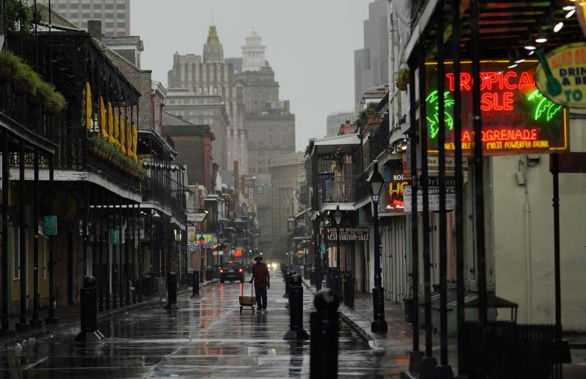 A man pulls a cart down a mostly deserted Bourbon Street in the French Quarter as the early effects of Hurricane Ida are felt, Sunday, Aug. 29, 2021, in New Orleans, La.