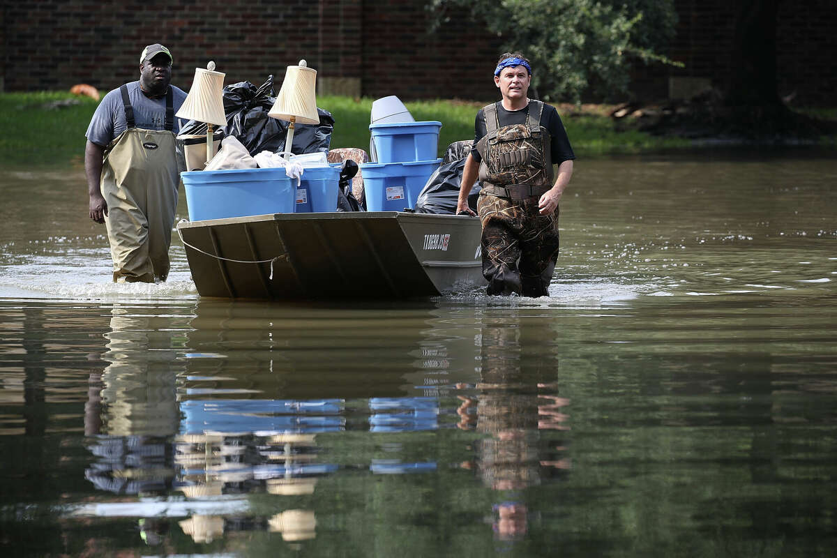 LaMarcus McCray and Allan Sommer (L-R) push a boat through a flooded neighborhood as they help bring items out of a friend's home in an area where a mandatory evacuation was under effect on September 3, 2017 in Houston, Texas.