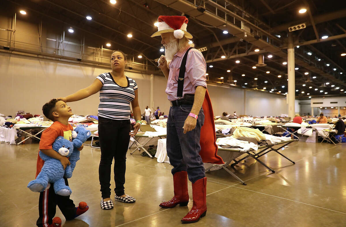 Giles Debenport (R) with Lone Star Santas Charities talks with evacuees while passing out toys at the NRG Center evacuation center on September 3, 2017 in Houston, Texas.