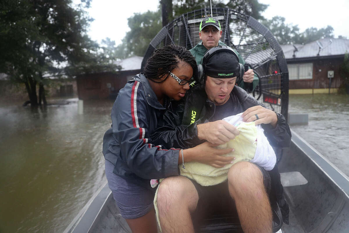 Shardea Harrison looks on at her three-week-old baby Sarai Harrison being held by Dean Mize as he and Jason Legnon used his airboat to rescue them from their home after the area was inundated with flooding from Hurricane Harvey on August 28, 2017 in Houston, Texas.