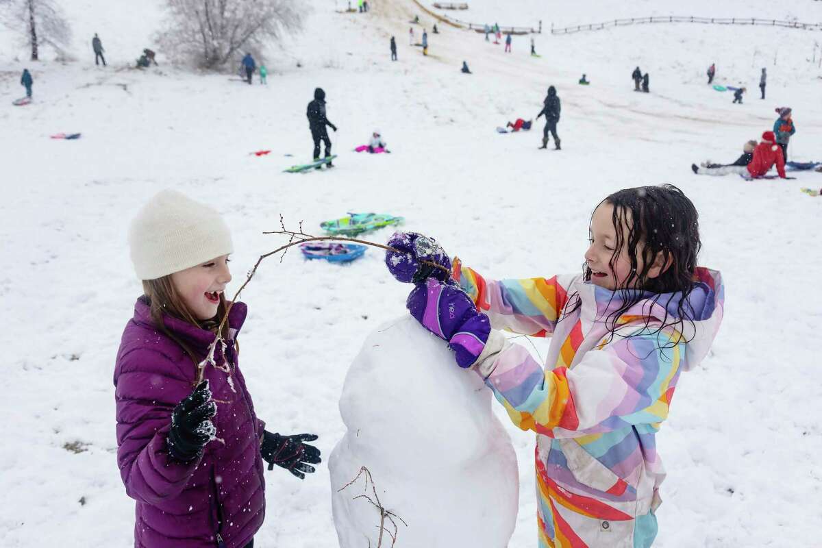 Friends Addie Palmer, 7, left, and Esther Roghaar, 7, right, use tree branches to make arms and even hair on their snowman at Camel's Back Park in Boise, Idaho, on Monday, Dec. 12, 2022. The National Weather Service reported 2.5 inches of snow accumulation overnight from their location at the Boise Airport. No more snow is in the forecast for the Boise area this week, but temperatures are expected to drop to as low as 6 degrees by Saturday night. (Sarah A. Miller/Idaho Statesman via AP)