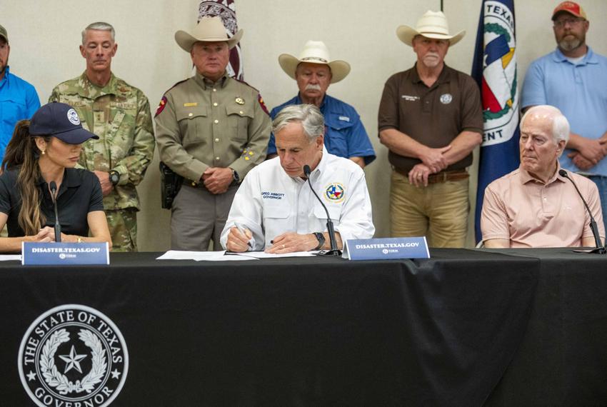 U.S. Secretary of Homeland Security Kristi Noem, left, and U.S. Sen. John Cornyn, right, look on as Texas Gov. Greg Abbott signs an emergency proclamation during a press conference in Kerrville.